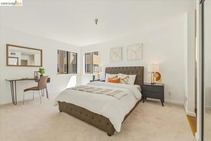 Carpeted room featuring multiple windows, white walls, and a built-in mirrored closet