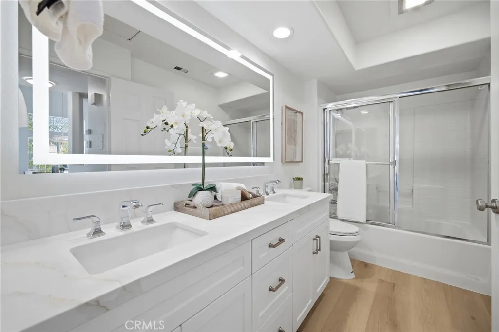 Remodeled full bath with white cabinet, quartz countertops, and LED mirror.