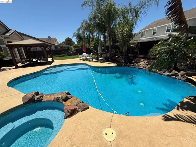 Resort-style backyard featuring a lagoon-shaped pool with integrated spa