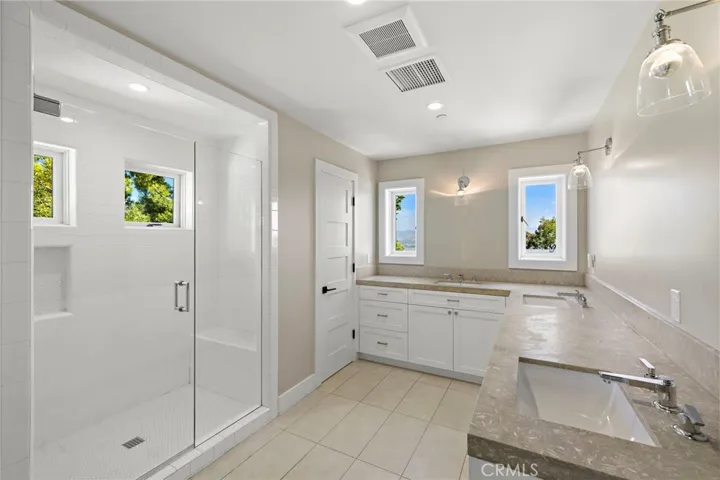 well-appointed hall bathroom featuring three sinks and a spacious walk-in shower.