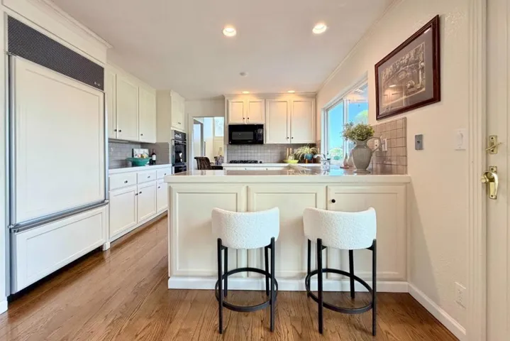 Bright kitchen with breakfast bar seating and built-in appliances.
