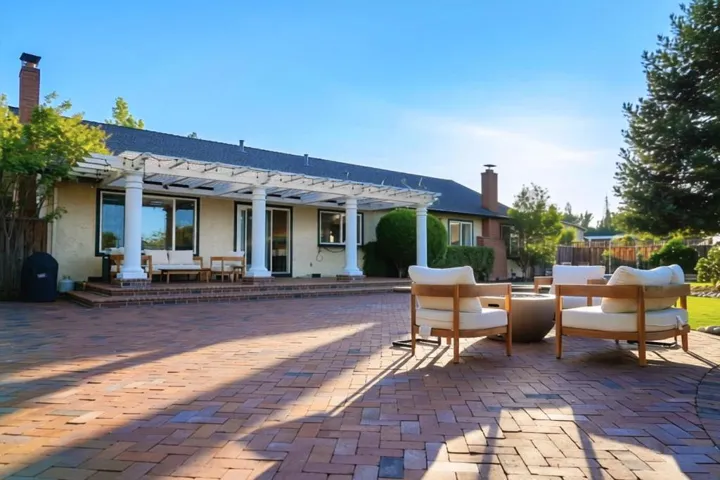 Backyard with lawn and mature landscaping. Covered patio with backyard access.