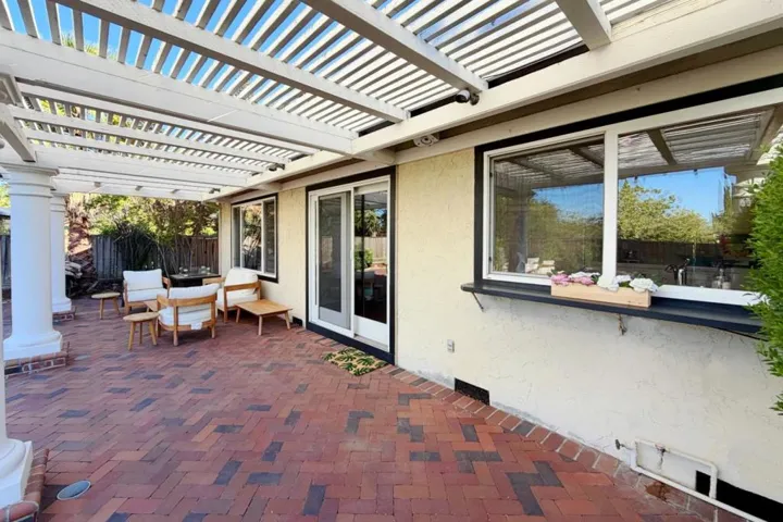 Backyard with lawn and mature landscaping. Covered patio with backyard access.