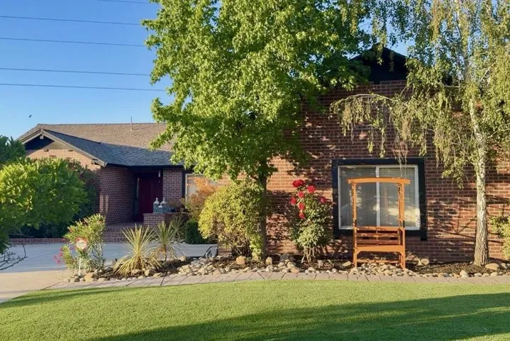 Front exterior view with mature trees and landscaped yard.