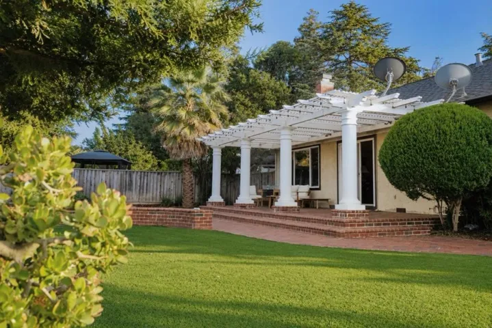 Backyard with lawn and mature landscaping. Covered patio with backyard access.