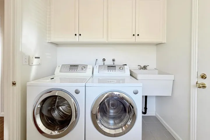 Laundry room with utility sink and storage cabinets.
