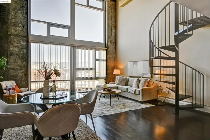 Loft-style living area featuring a spiral staircase, expansive windows, dark wood-finish flooring, and exposed concrete architectural elements