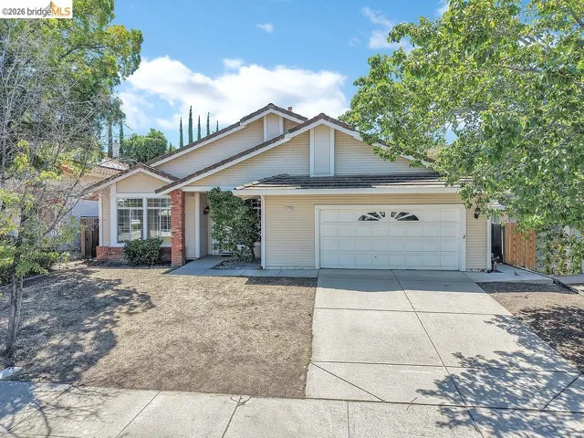 Single-story residence featuring a two-car garage with a decorative window, a concrete driveway, and a paved walkway leading to the front entry