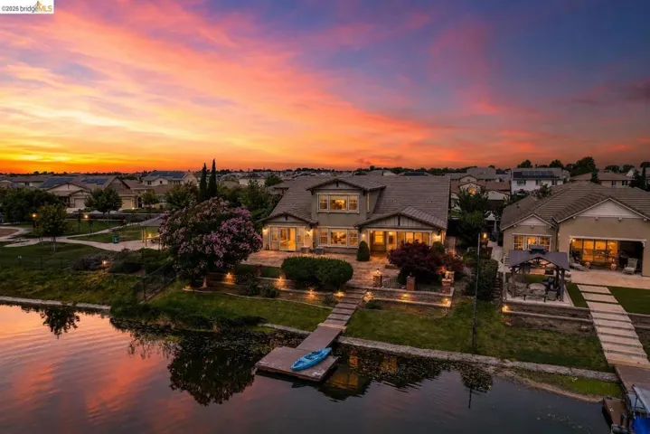 Waterfront property featuring a private dock, expansive patio, and mature landscaping
