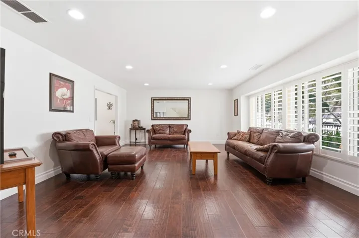 Spacious living room features recessed lighting, plantation shutters