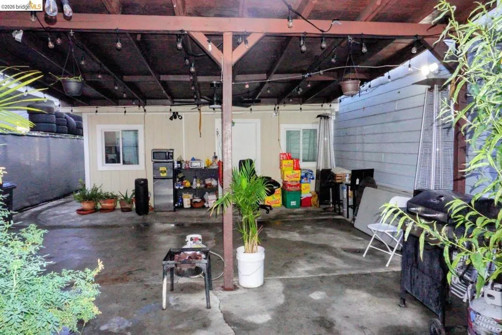 Covered patio space featuring an open-beam roof structure and concrete flooring