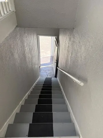 Stairwell with textured walls and a handrail