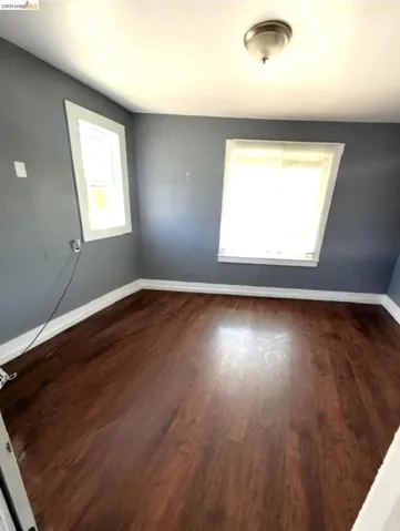 Room featuring wood-finish flooring, two windows, and a flush mount ceiling light