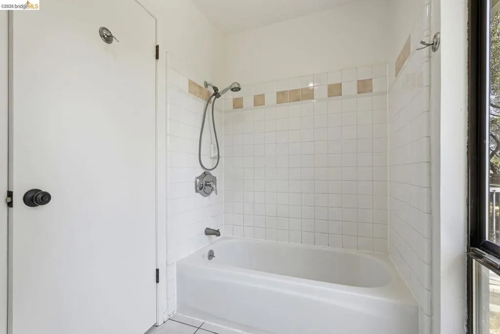 White tiled shower over tub with a decorative accent tile band