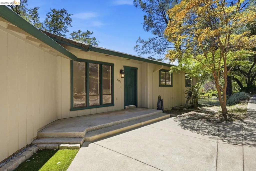 Light-colored siding exterior with dark green trim and a matching front door