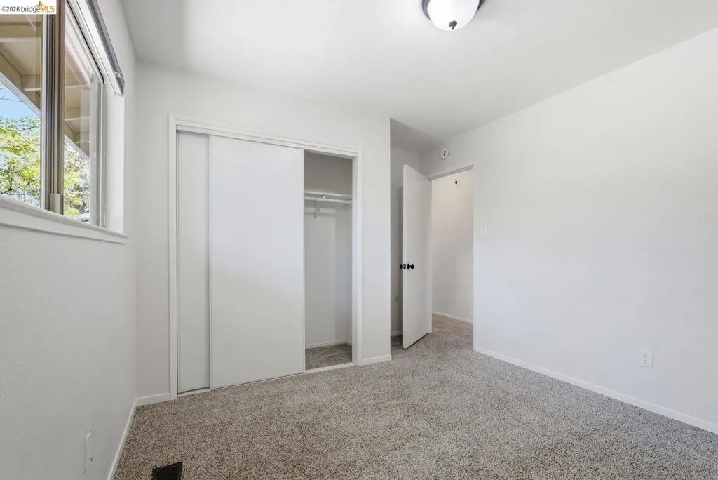 Interior space featuring light gray textured carpeting, a white sliding closet door, and a white window frame