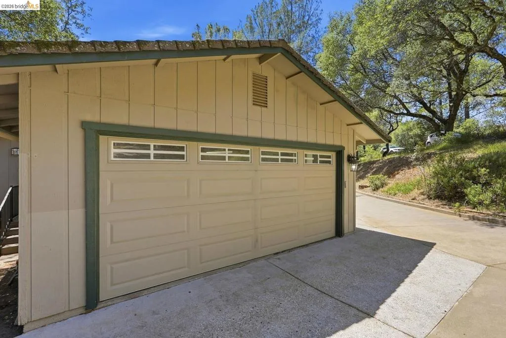 Two-car garage with panel-style door and upper window inserts, framed by board-and-batten siding and a green trim accent