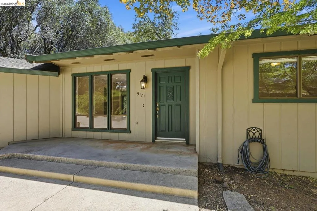Exterior siding with a green trim, featuring a concrete patio