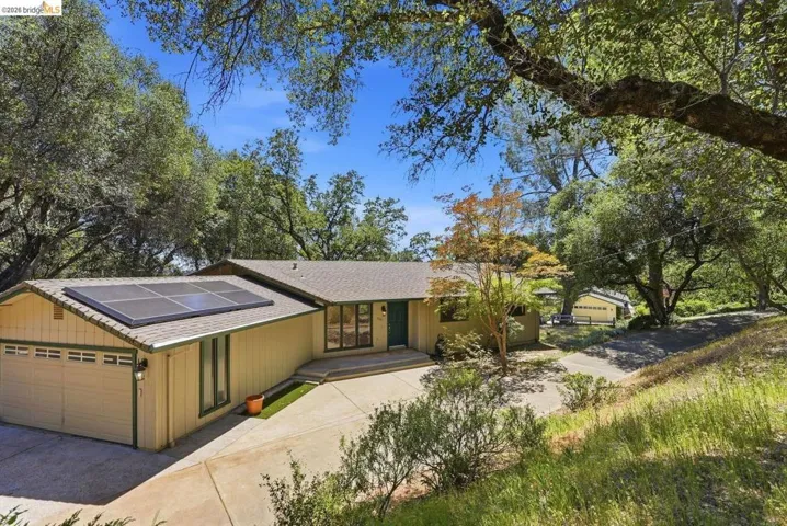 Ranch-style exterior with attached two-car garage, solar panels, and a concrete driveway