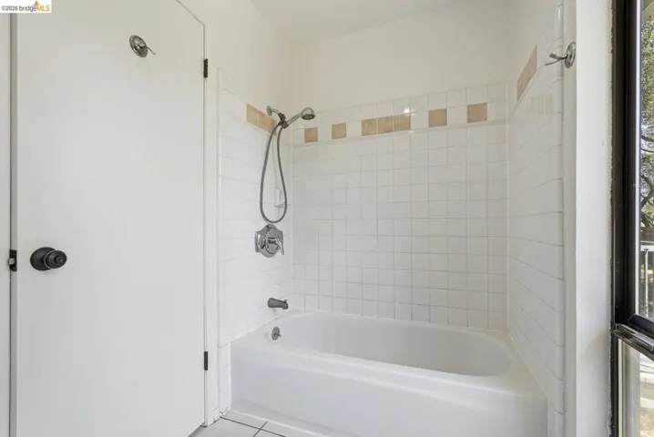 White tiled shower over tub with a decorative accent tile band