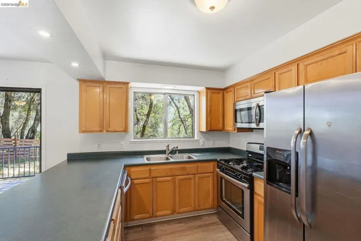Kitchen featuring wood-finish cabinetry, dark countertops, and stainless steel appliances