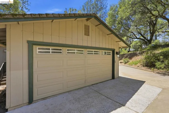 Two-car garage with panel-style door and upper window inserts, framed by board-and-batten siding and a green trim accent