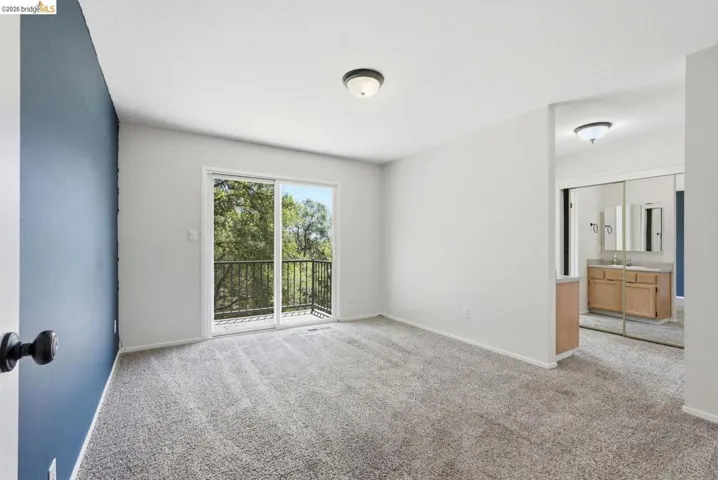 Room featuring a private balcony with black metal railings, light gray carpeting, and a blue accent wall