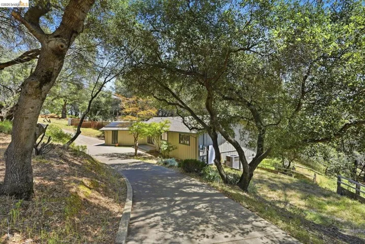 Asphalt driveway with concrete curbing leading to a single-story residence