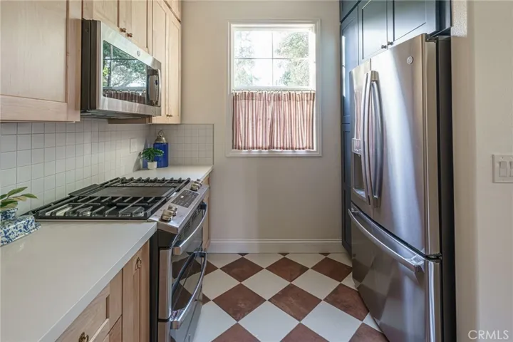 Galley kitchen with custom window coverings and new appliances that come with the home.