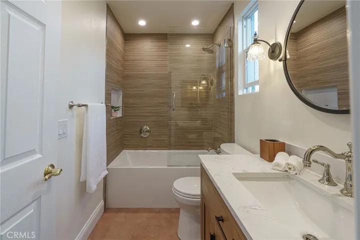 Large shower in deep bathtub with sublte porcelin tile work, polished nickel Brizo hardware, custom fixtures and cabinets. New Kohler toilet.
