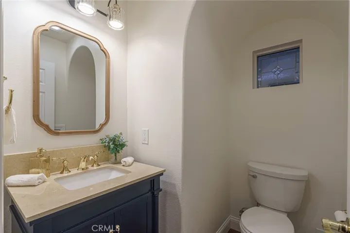 Tucked next to the stairs in the newly remodeled bathroom with custom vanity, gold Kohler fixtures, lighting and mirror in beautiful blues and gold. Remodeled from top to bottom.