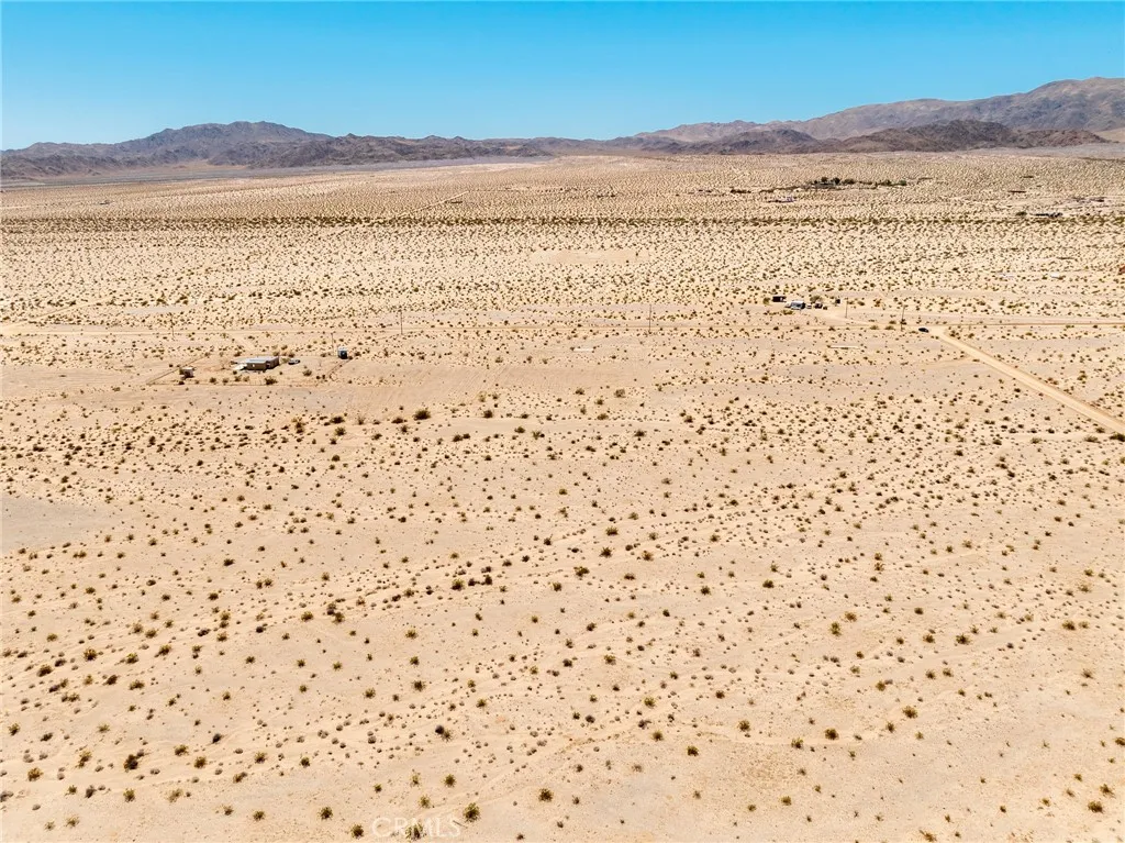 Expansive eastward-facing aerial shot highlighting the endless desert vistas surrounding this investment lot.