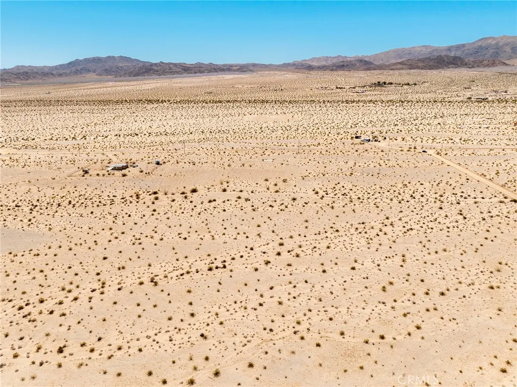 Expansive eastward-facing aerial shot highlighting the endless desert vistas surrounding this investment lot.