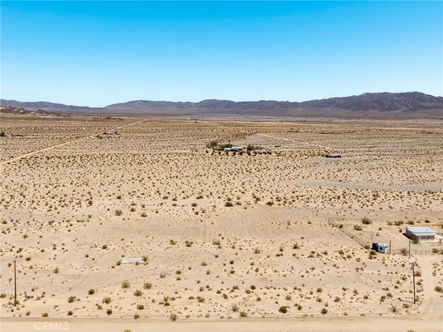 Wide aerial perspective of the premium 5-acre vacant tract in Wonder Valley, showing the expansive, level terrain and stunning high-desert horizon.