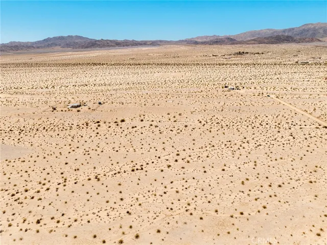Expansive eastward-facing aerial shot highlighting the endless desert vistas surrounding this investment lot.