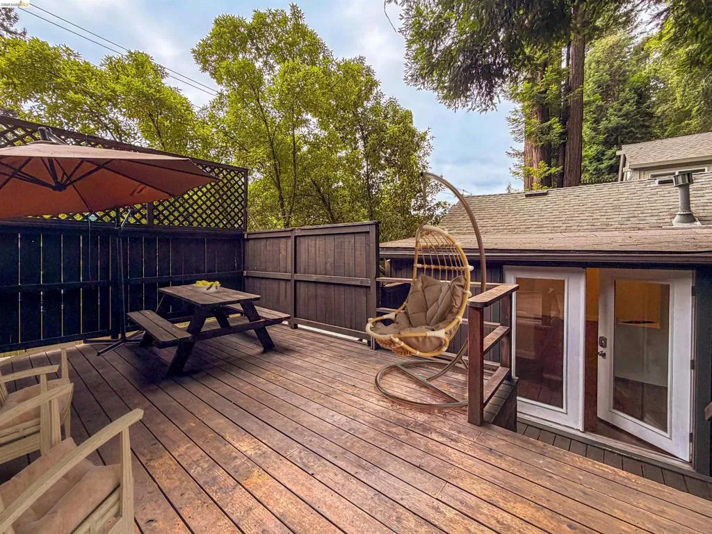 Expansive exterior deck featuring durable wood-finish flooring, dark wood privacy fencing, and direct access through a set of double French doors