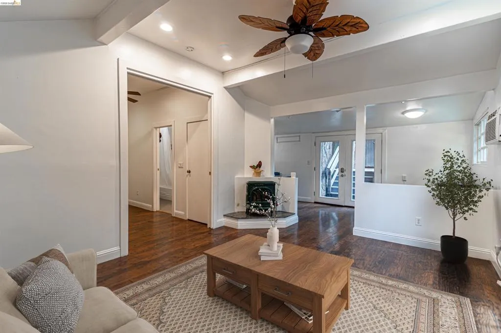 Open-concept living area featuring rich wood-finish flooring, a decorative corner fireplace, and recessed lighting