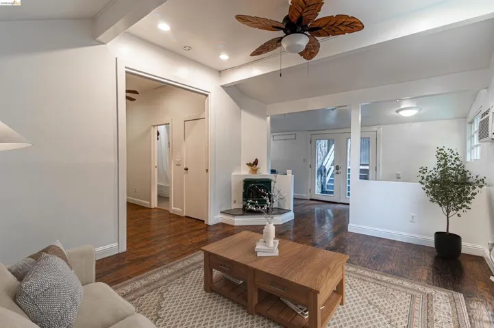 Open-concept living area featuring rich wood-finish flooring, a decorative corner fireplace, and recessed lighting