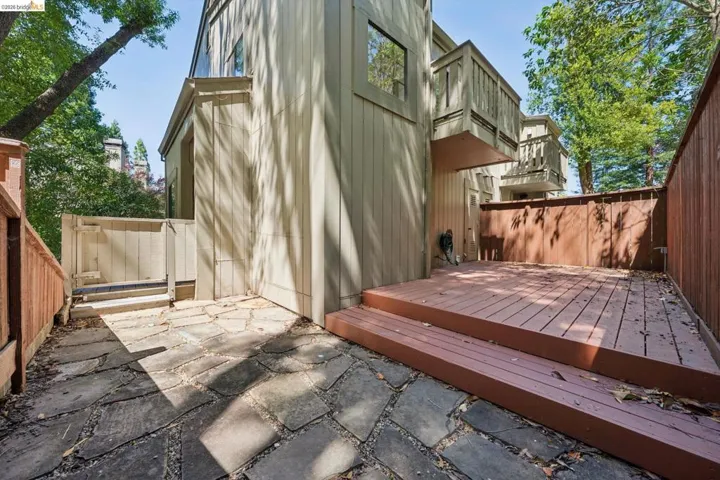 Private outdoor patio featuring a flagstone walkway, elevated wood deck, and wood fencing