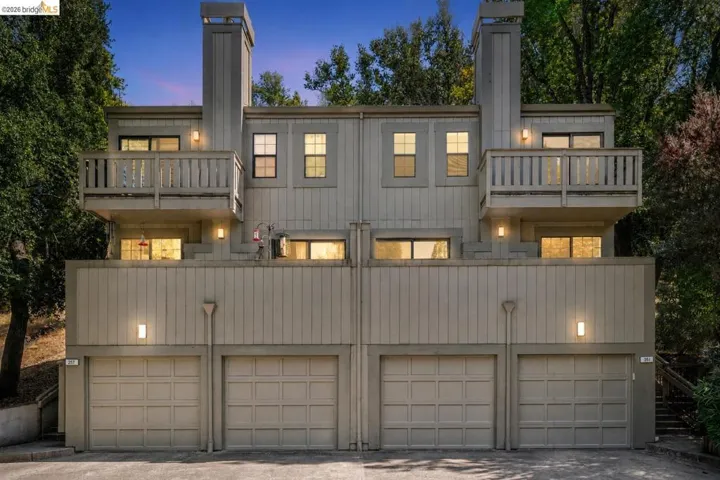 Multi-level property featuring two balconies, dual chimneys, and individual garage access