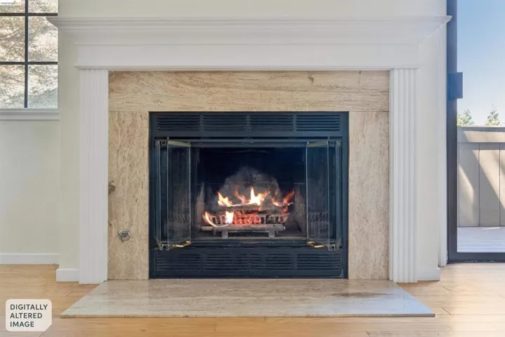 Fireplace featuring a stone surround, white mantel, and wood-finish flooring