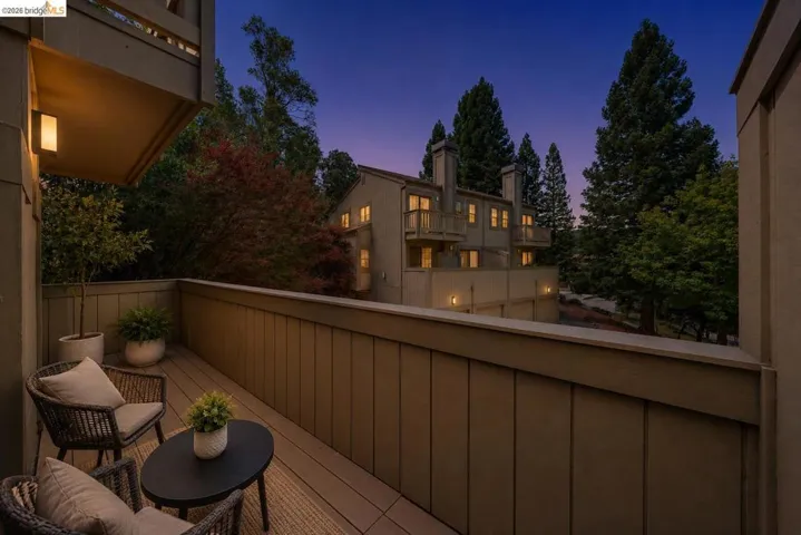 Private balcony featuring composite decking, a panelled railing, and an exterior wall light