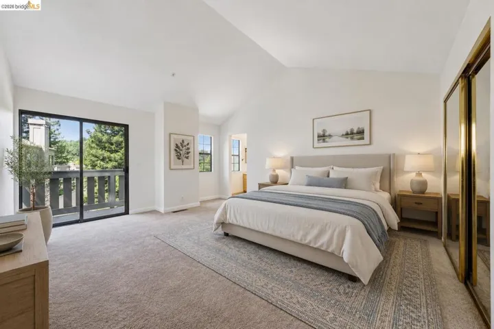 Carpeted bedroom featuring a vaulted ceiling and a sliding glass door opening to a private balcony