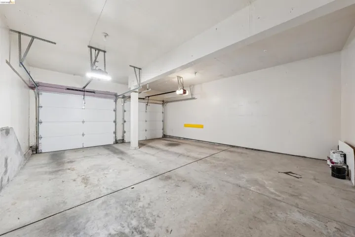 Spacious garage featuring two sectional overhead doors, concrete flooring, and overhead lighting fixtures