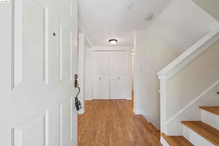 Entry foyer featuring wood-finish flooring, a white paneled entry door, and a staircase with wood treads