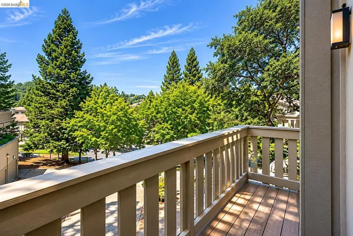 Private balcony featuring composite decking, a sturdy railing system, and an exterior wall-mounted light fixture