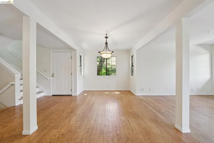 Spacious interior featuring wood-finish flooring, white walls, and a traditional chandelier