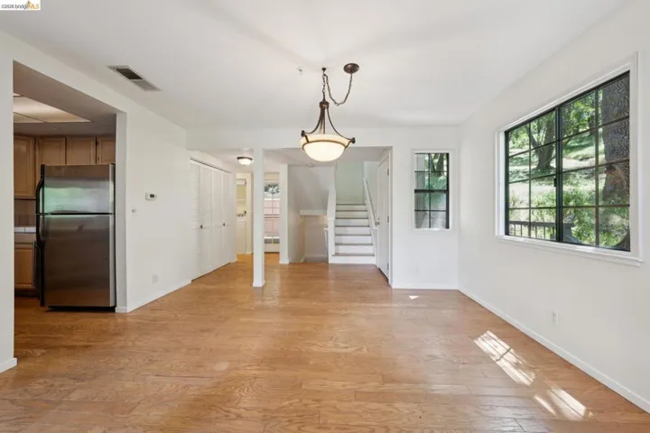 Expansive living area featuring wood-finish flooring, a contemporary ceiling light fixture, and multiple windows