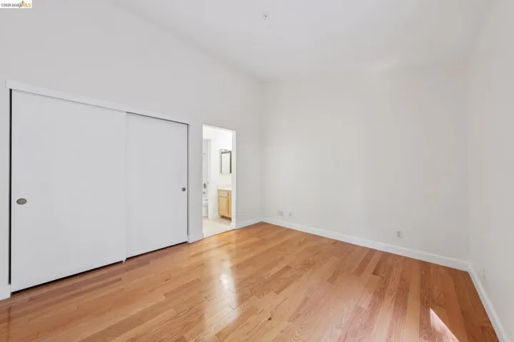 Room featuring wood-finish flooring, vaulted ceilings, and a double-door sliding closet