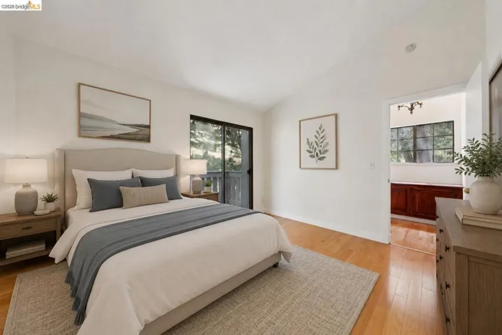 Bright bedroom featuring light wood-finish flooring and a vaulted ceiling
